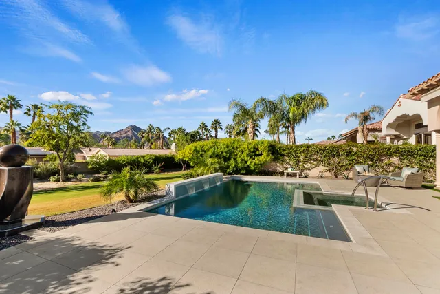 a view of a swimming pool with a lawn chairs and potted plants