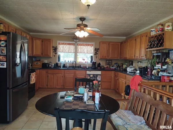 a kitchen with stainless steel appliances granite countertop a sink a stove a refrigerator cabinets and a dining table