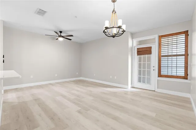 a view of an empty room with a chandelier fan and a window