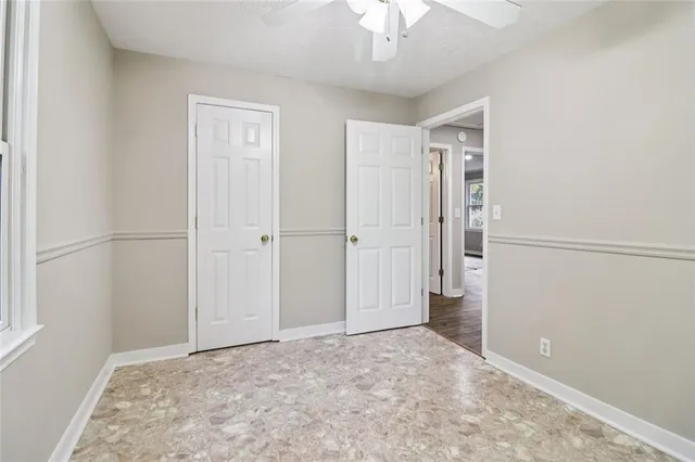 an empty room with chandelier fan and refrigerator
