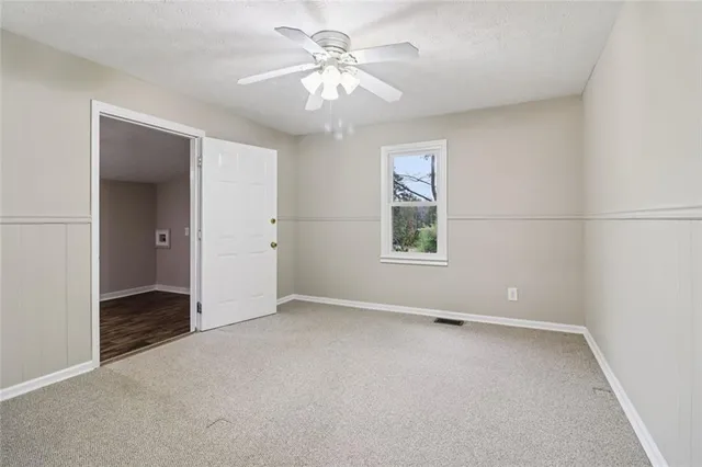 a view of a yard in front of a house with plants and large tree