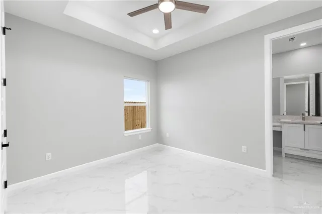 an empty room with a chandelier fan and windows