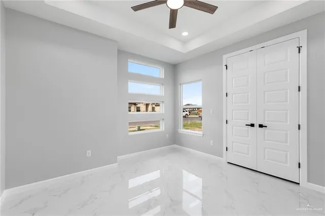 an empty room with windows and ceiling fan