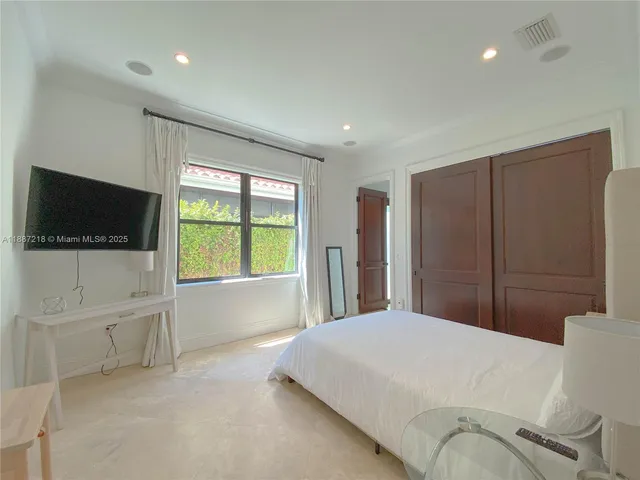 a large bedroom with a bed and a flat screen tv