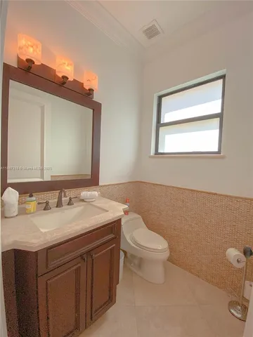 a bathroom with a granite countertop toilet sink and mirror