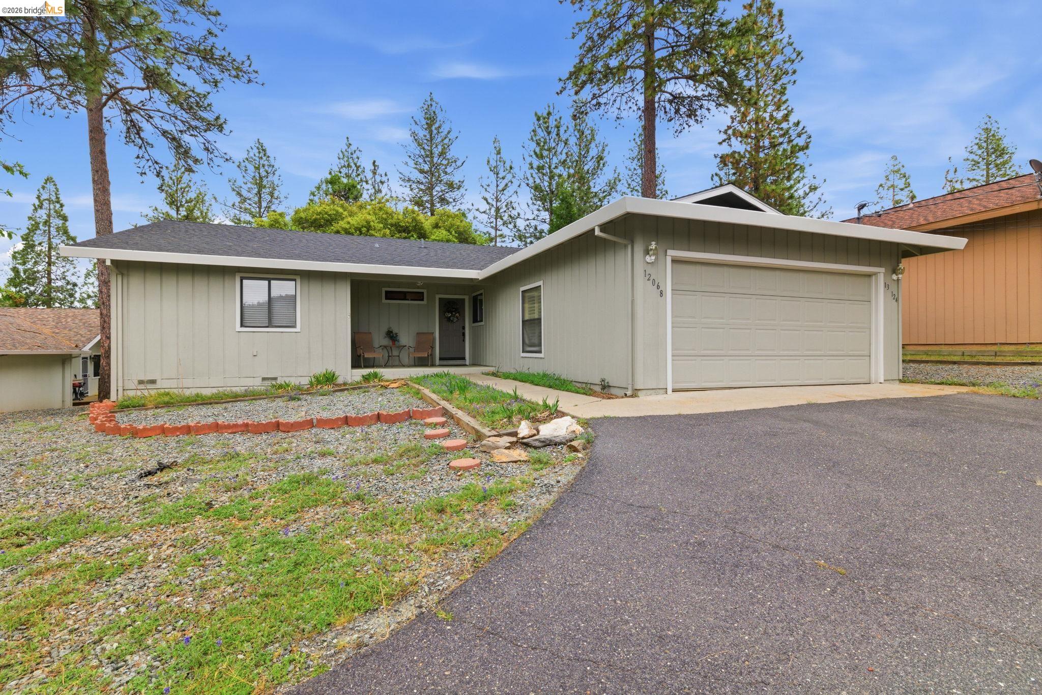 Ranch-style home with a garage, asphalt driveway, covered porch, and a shingled roof