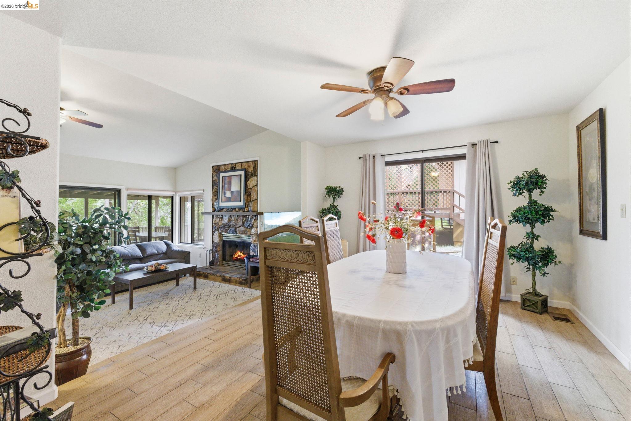 12068 Breckenridge Road Groveland, CA 95321 - Photo 16 of 55 Dining area featuring ceiling fan, wood finish floors, healthy amount of natural light, lofted ceiling, and a fireplace