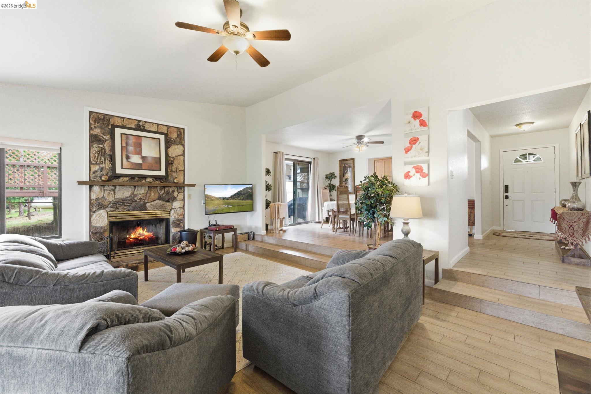 12068 Breckenridge Road Groveland, CA 95321 - Photo 8 of 55 Living area featuring hardwood / wood-style flooring, a stone fireplace, and a ceiling fan