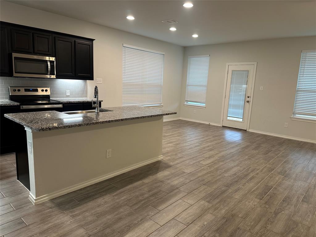 1613 Abbottsford Avenue Providence Village, TX 76227 - Photo 11 of 14 a kitchen with stainless steel appliances granite countertop a stove a sink and a microwave