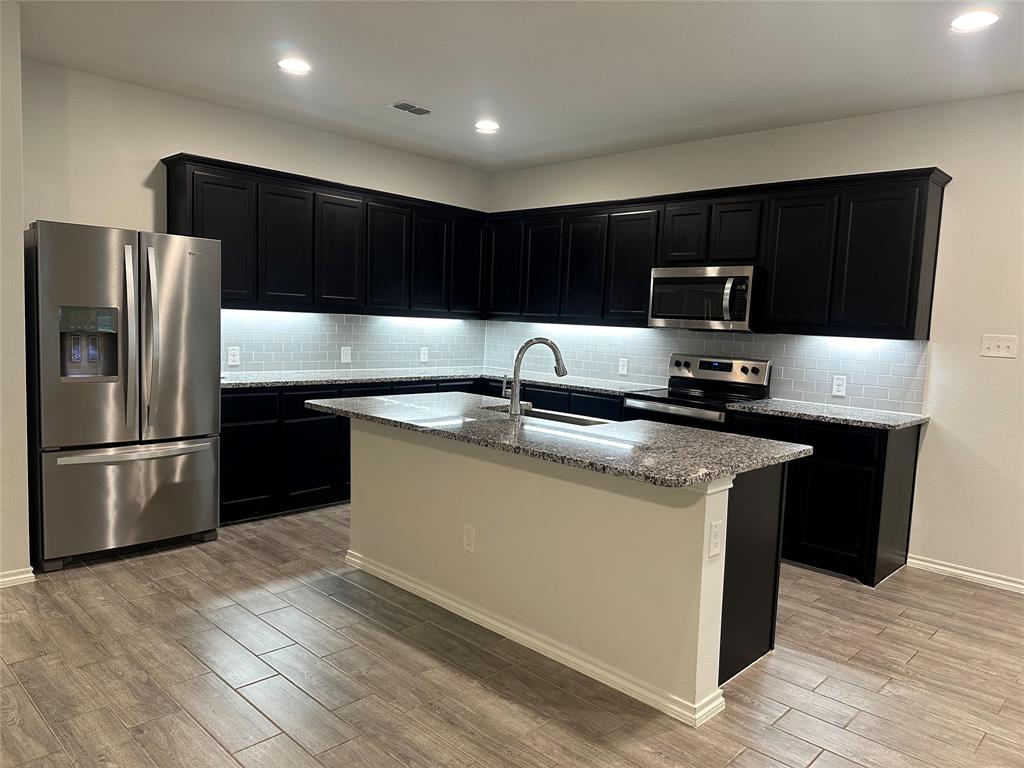 1613 Abbottsford Avenue Providence Village, TX 76227 - Photo 8 of 14 a kitchen with stainless steel appliances wooden cabinets a sink and a refrigerator