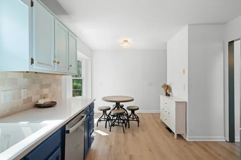 a kitchen with stainless steel appliances dining table chairs and wooden floor