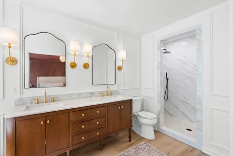 a bathroom with a double vanity sink and mirror with toilet