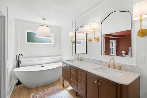 a bathroom with a double vanity sink mirror and bathtub