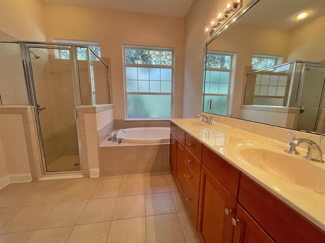a spacious bathroom with a tub sink and mirror
