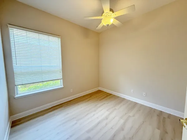 an empty room with a window and a fan