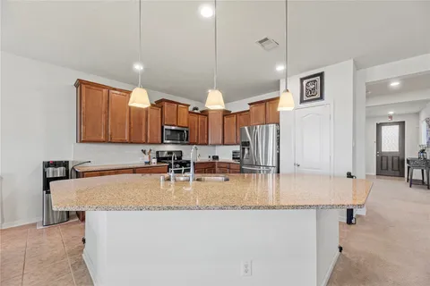 a large kitchen with kitchen island granite countertop a sink a stove counter space and cabinets