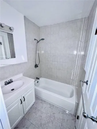 a bathroom with a white bath tub a sink and a mirror