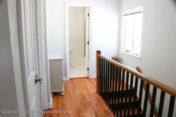a view of a hallway with wooden floor and a bathroom