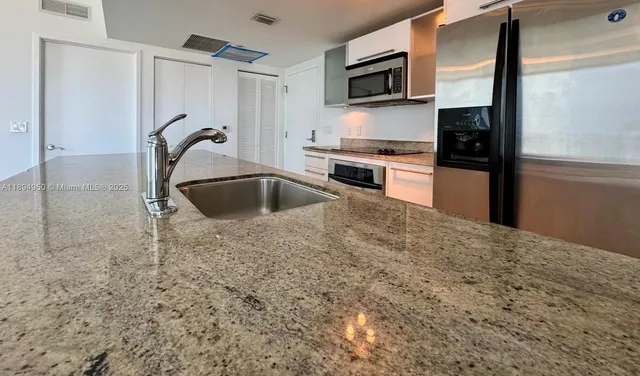 a kitchen with kitchen island a sink stainless steel appliances and cabinets
