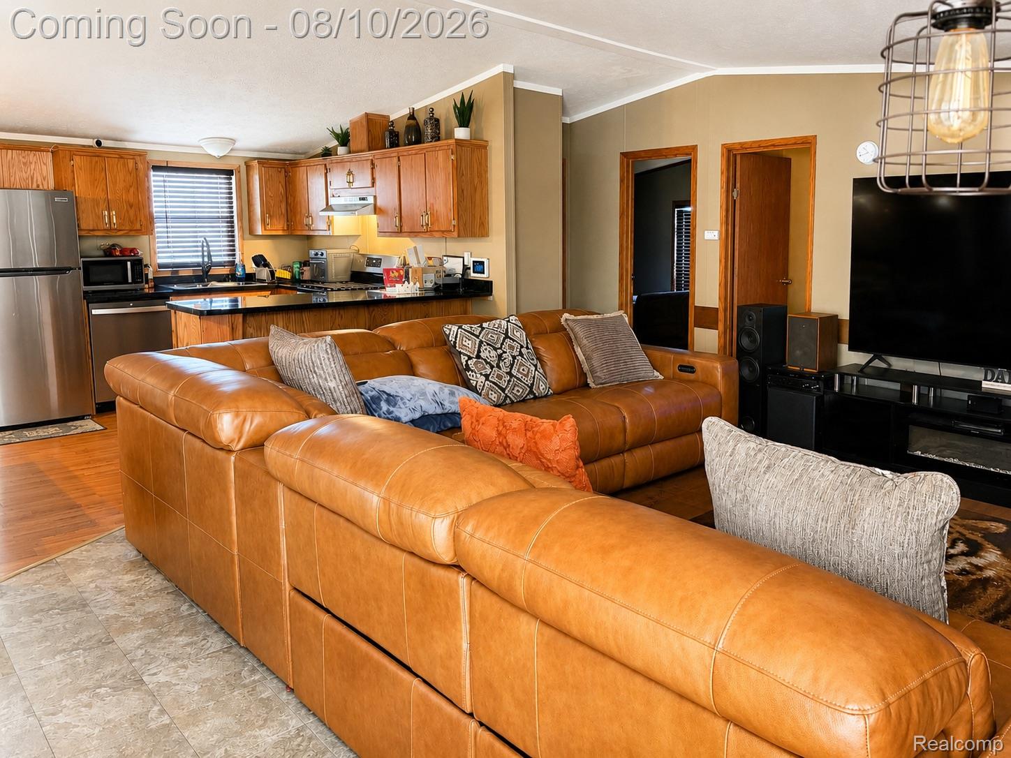 3730 Lapeer Road Port Huron, MI 48060 - Photo 5 of 18 Open concept living area with kitchen, stainless steel appliances, wood-finish cabinetry, black countertops, and wood-finish flooring
