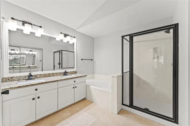 a bathroom with a double vanity sink mirror and bathtub