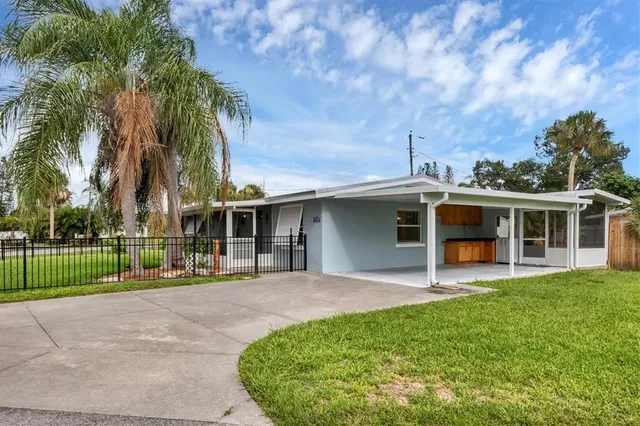 a view of a house with a yard and palm trees