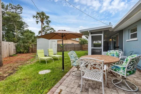 a view of a chair and table in backyard of the house