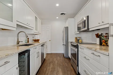 a kitchen with stainless steel appliances granite countertop a sink stove refrigerator and cabinets