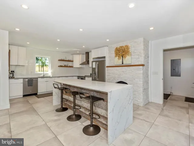 a kitchen with stainless steel appliances granite countertop a stove a sink a dining table and chairs