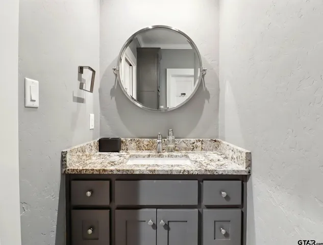a bathroom with a granite countertop sink and a mirror
