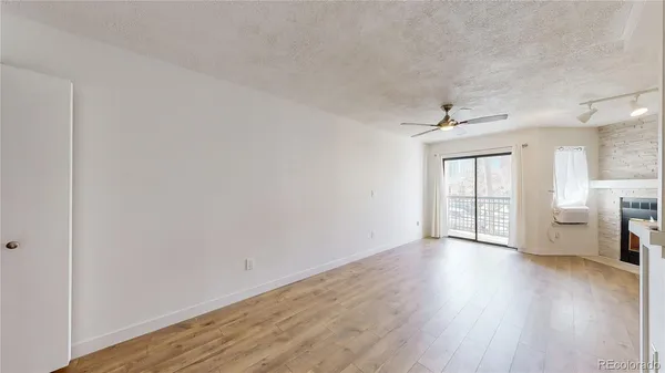 a view of an empty room with a window and wooden floor
