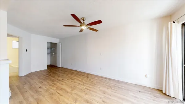a view of a big room with wooden floor and a ceiling fan