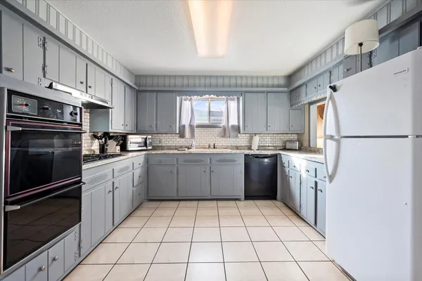 a group of chairs sitting in a kitchen with white cabinets