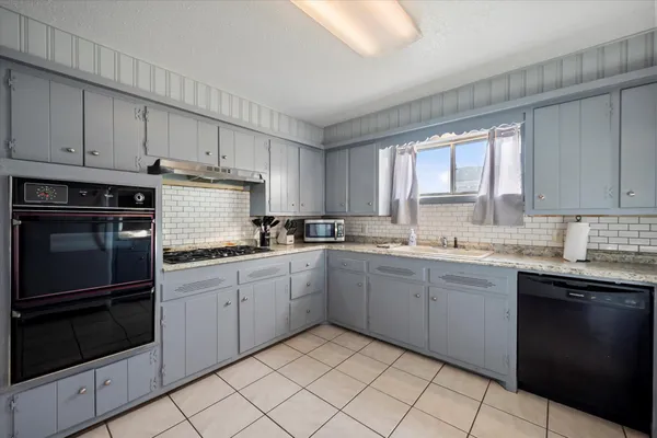 a kitchen with granite countertop stainless steel appliances white cabinets sink and window
