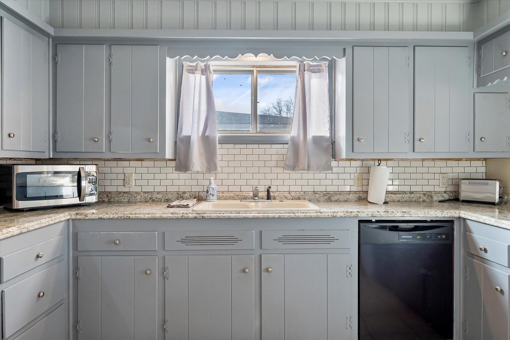 4904 15th Street Lubbock, TX 79416 - Photo 25 of 29 a kitchen with granite countertop stainless steel appliances white cabinets sink and window