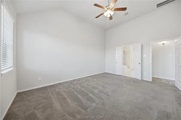 an empty room with chandelier fan and windows