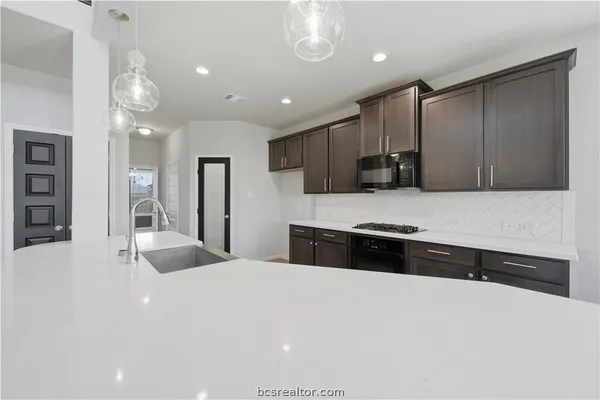 a large white kitchen with a large counter top space appliances and cabinets