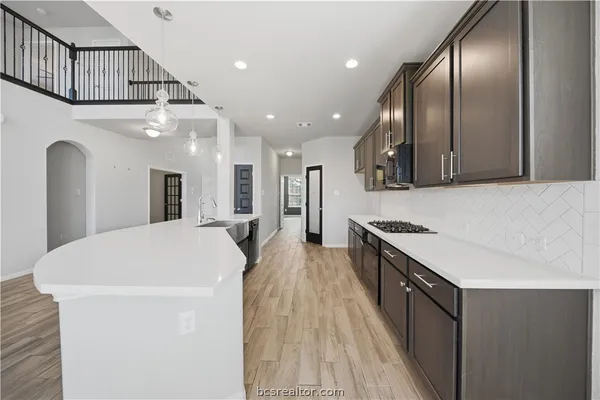 a large kitchen with stainless steel appliances a large counter top a stove and a refrigerator