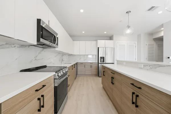 a large kitchen with stainless steel appliances granite countertop a sink a stove and a refrigerator