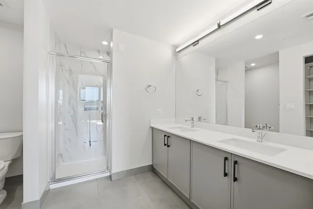 a bathroom with a double vanity sink mirror and shower