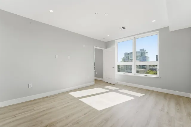 an empty room with wooden floor and windows