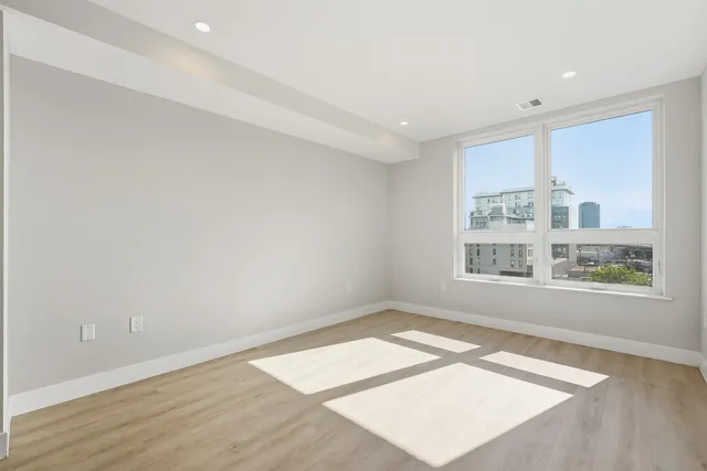 an empty room with wooden floor and windows