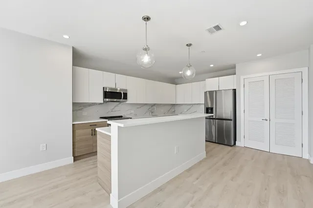 a kitchen with stainless steel appliances kitchen island a refrigerator sink and microwave