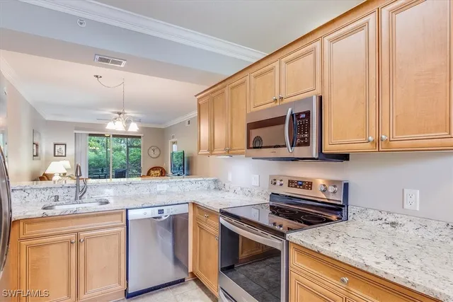 a kitchen with stainless steel appliances granite countertop a sink a stove a microwave and wooden cabinets