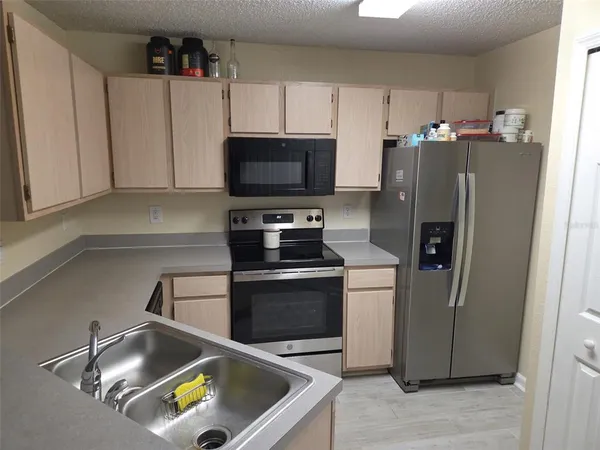 a kitchen with stainless steel appliances a refrigerator a sink a stove a microwave and wooden cabinets