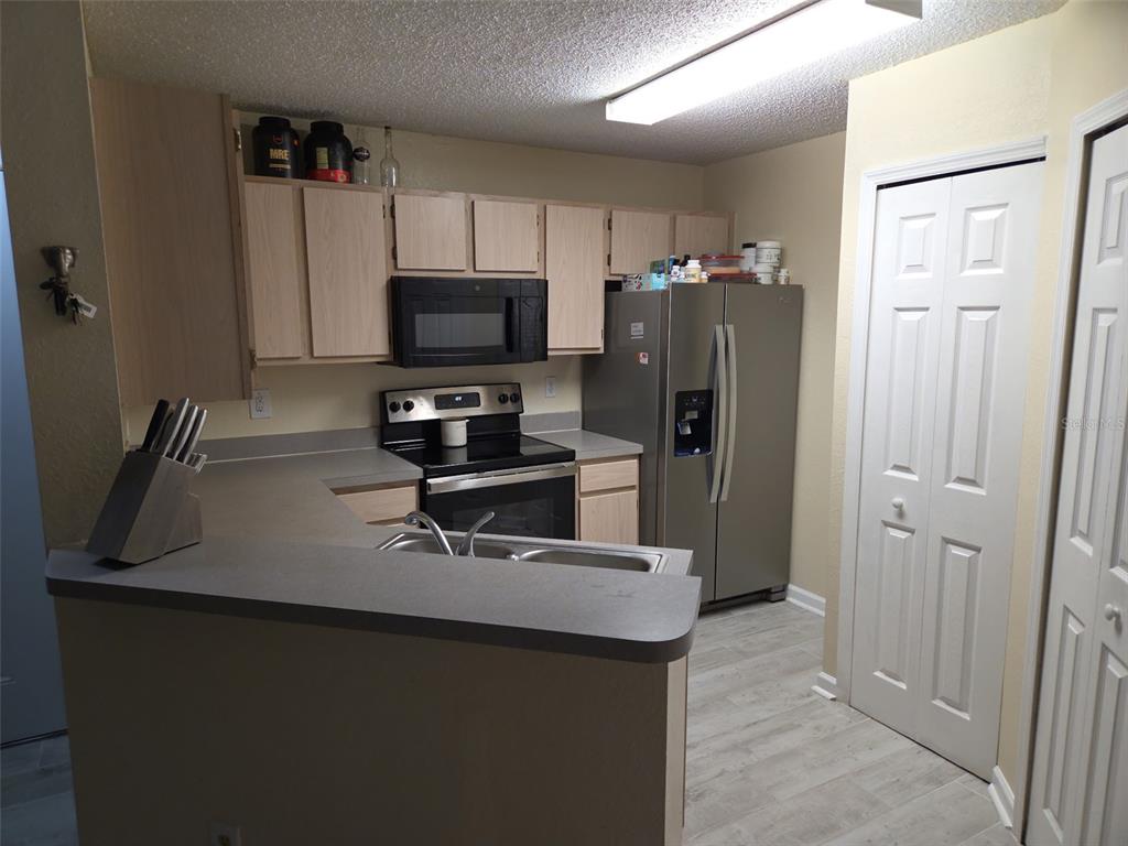 3705 Southwest 27th Street, Unit 422 Gainesville, FL 32608 - Photo 15 of 25 a kitchen with stainless steel appliances a refrigerator a sink a stove a microwave and wooden cabinets