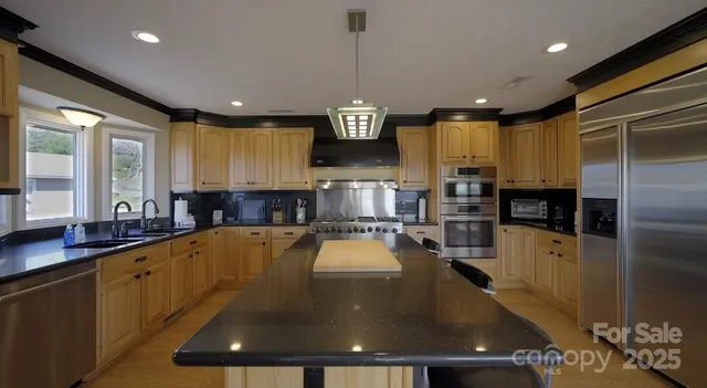 a kitchen with stainless steel appliances kitchen island granite countertop a refrigerator and a stove top oven