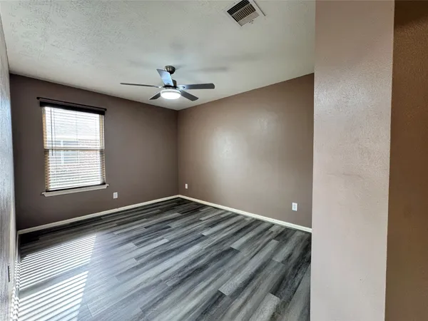 an empty room with windows and fan