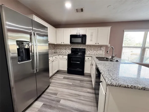 a kitchen with stainless steel appliances granite countertop a refrigerator a stove and a sink