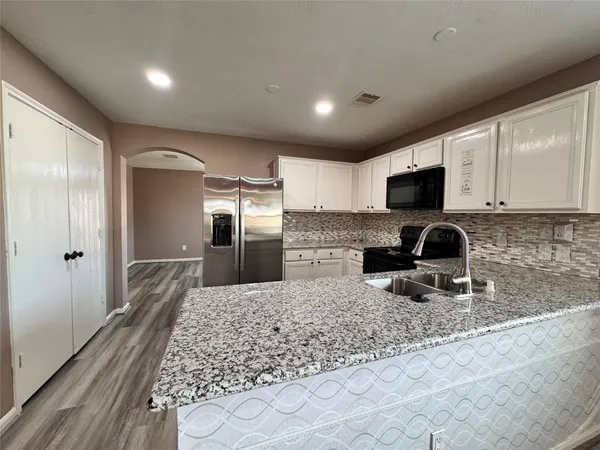 a large kitchen with granite countertop a refrigerator and a sink